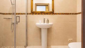 Ein Badezimmer mit Duschkabine aus Glas, einem Standwaschbecken und einer Toilette.