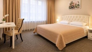 Ein Hotelzimmer mit Bett, Schreibtisch, Stuhl und einem Bild an der Wand.