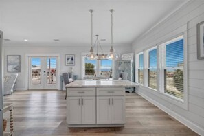 A spacious kitchen with a large island, pendant lighting, and a view of the outdoors. - Luxury Beach House 50 Steps To Beach / Heated Pool (Gulf Shores)