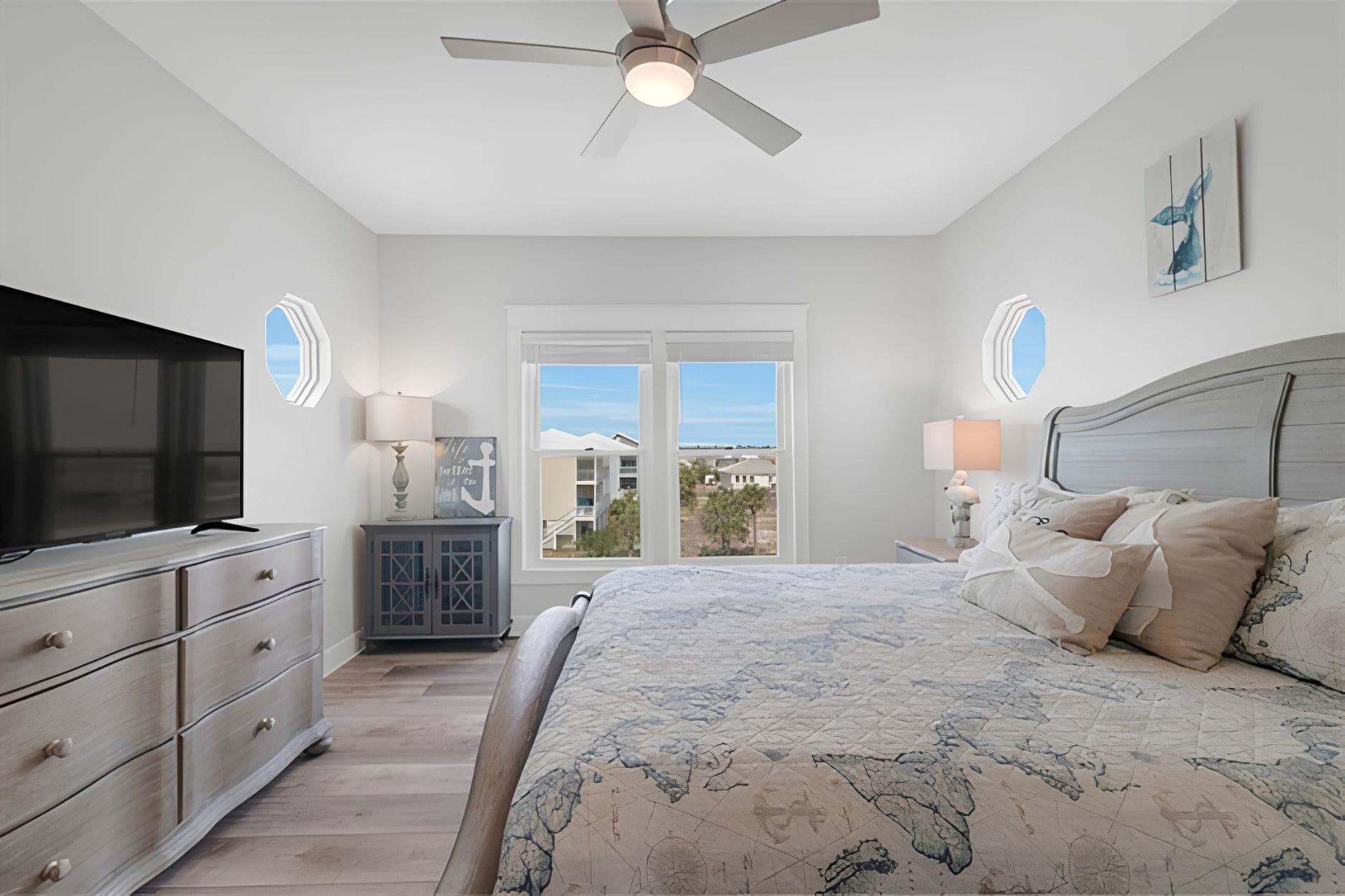A bedroom with a bed, a television, a dresser, a nightstand, and a ceiling fan.