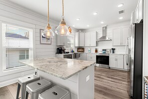 A modern kitchen with white cabinetry, a marble island, stainless steel appliances, and pendant lighting. - Luxury Beach House 50 Steps To Beach / Heated Pool (Gulf Shores)