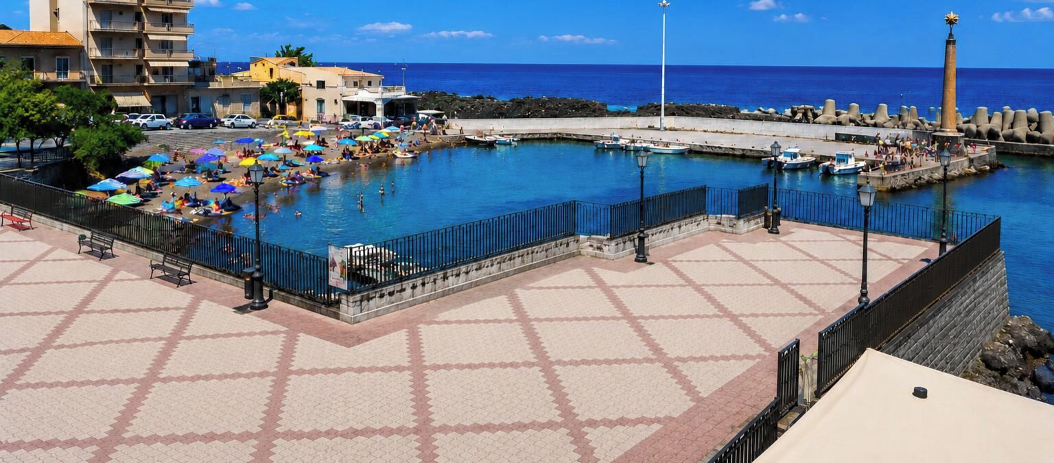 Eine Küstenpromenade mit befestigtem Gehweg, einem Schwimmbad und einem Steg mit Booten.