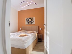 A bedroom with a bed, bedside lamps, a wall-mounted artwork, and a door. - BUKY Escape by Interhome (Mladé Buky)