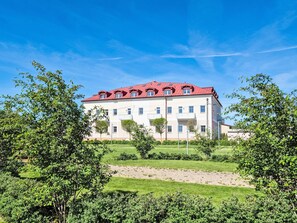 A multi-story building with a red roof, surrounded by greenery and a clear sky. - BUKY Escape by Interhome (Mladé Buky)