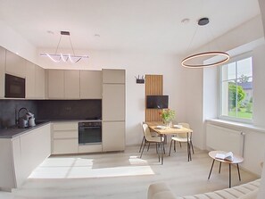 Een moderne keuken met inbouwapparatuur, een eethoek met een tafel en stoelen, en een groot raam met uitzicht op het omliggende landschap.