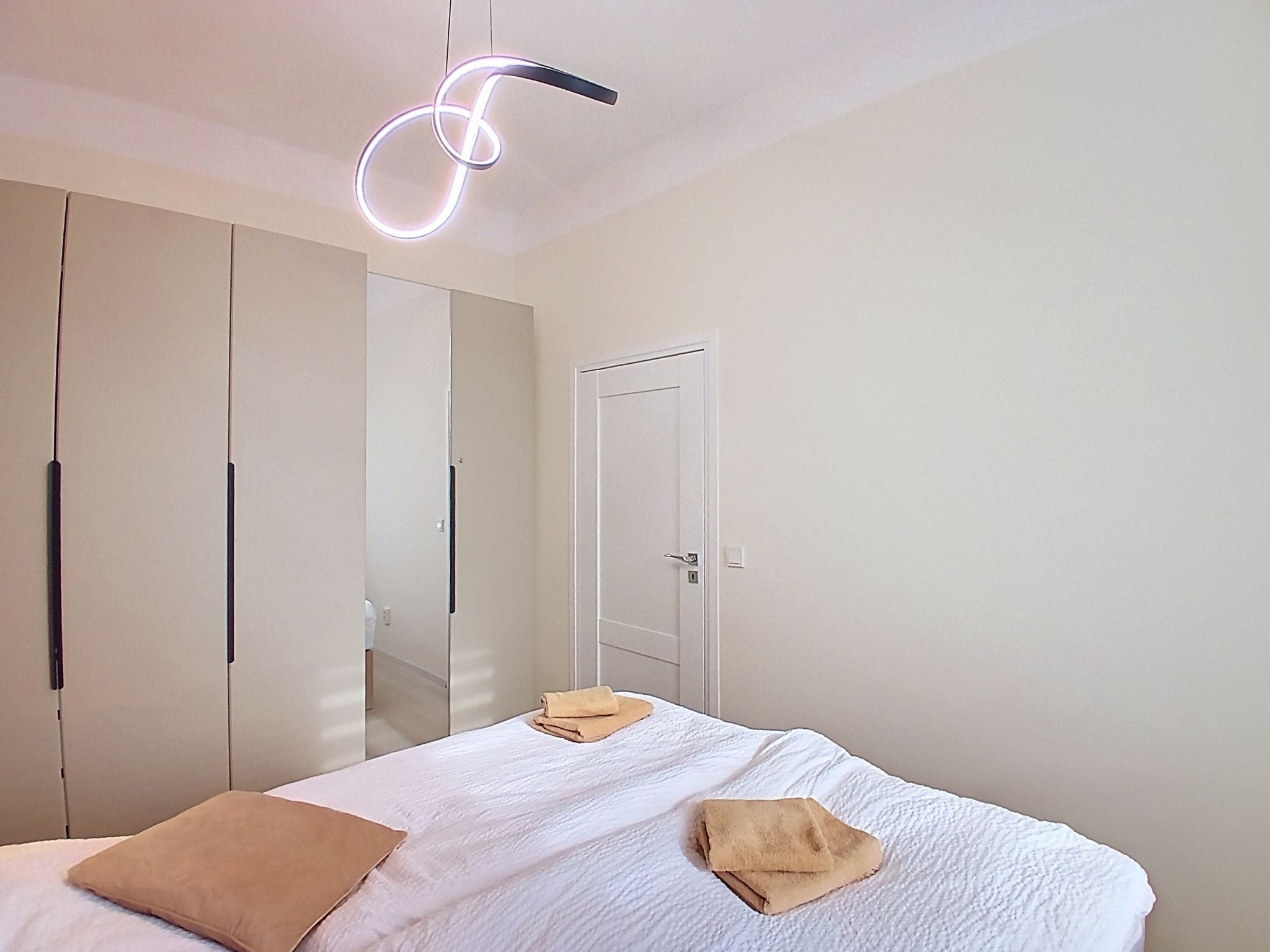 A bedroom with a bed, a wardrobe, and a door.