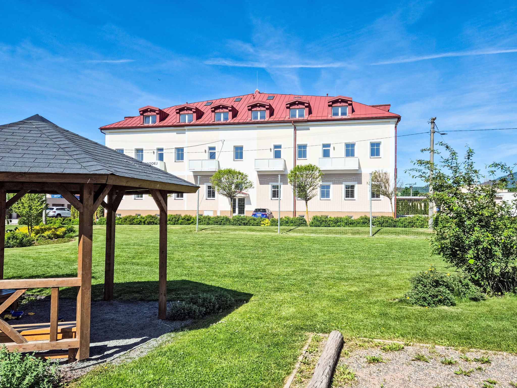 A building with a red roof, multiple windows, and a fenced yard.