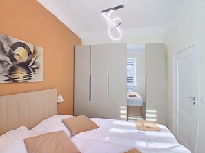 Ein Schlafzimmer mit Bett, einem Kopfteil, einem Wandbild und einem Schrank mit Spiegel.