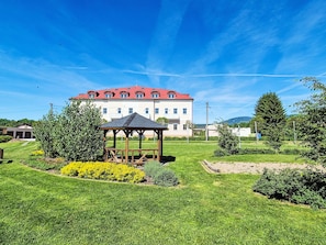 A building with a red roof, a gazebo, and well-maintained grass and flower beds. - BUKY Escape by Interhome (Mladé Buky)