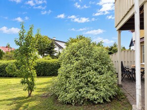 A residential property with a well-maintained garden, a patio with outdoor furniture, and a house with a red roof. - Cityhuset by Interhome (Falkenberg)