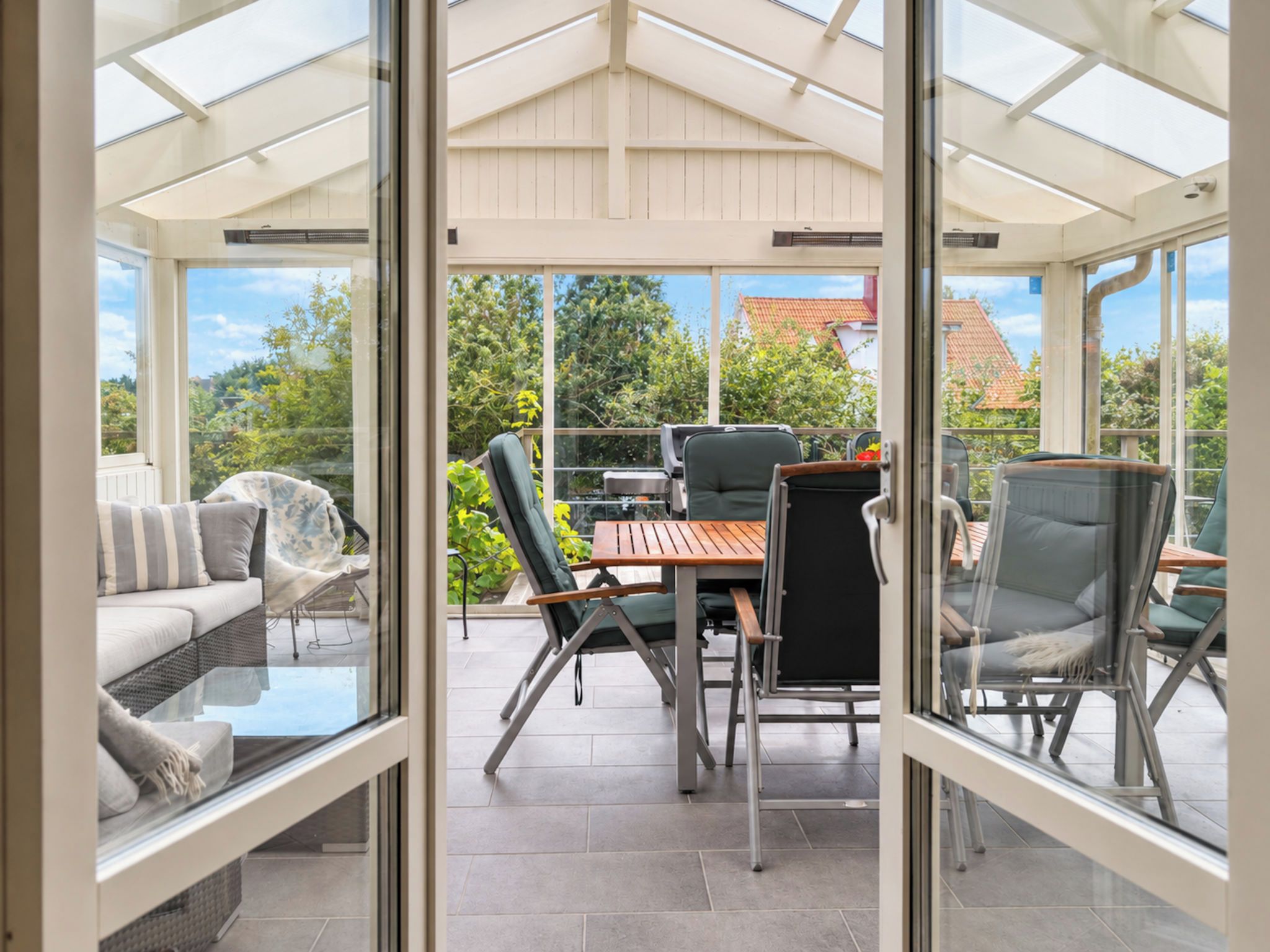 Ein Wintergarten mit Glasdecke, einem Esstisch, Stühlen und einer Couch.