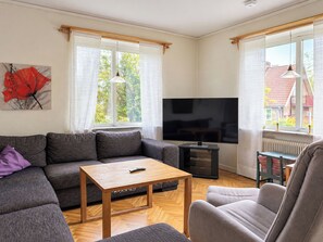 Ein modernes Wohnzimmer mit einem grauen Sofa, einem Holztisch, einem Flachbildfernseher und einem kleinen Tisch mit einem Heizgerät.