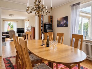 Ein Essbereich mit Holztisch, Stühlen, einer Chandelierleuchtre und einem Bücherregal mit Büchern und einem Fernseher.
