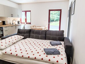 Un dormitorio con cama, sofá, zona de cocina y mesa de comedor.