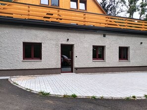 A building with a wooden upper floor, a paved entrance area, and a single door. - Pod Smrkem by Interhome (Janov nad Nisou)