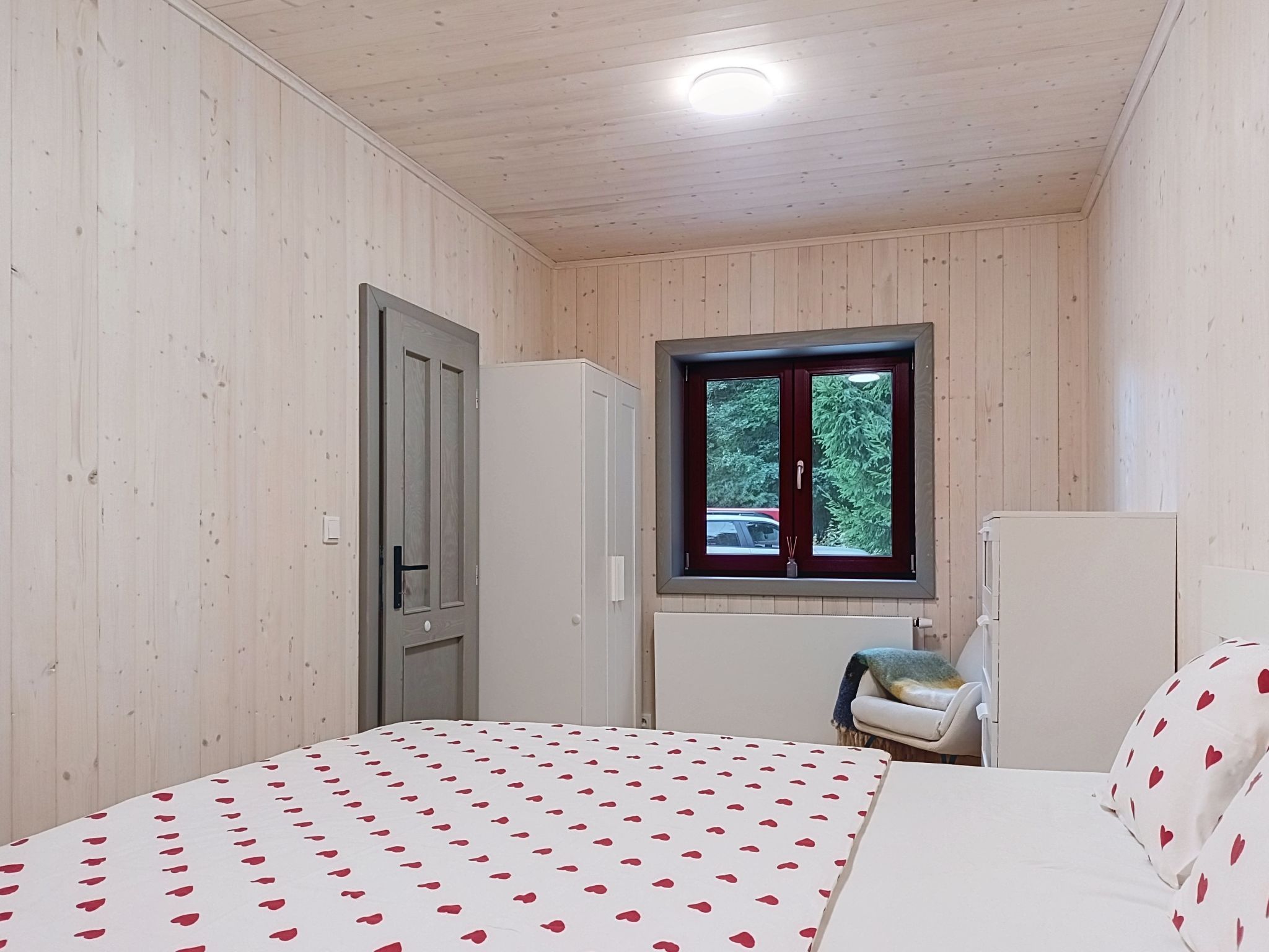 A bedroom with a bed, a window, and a door.