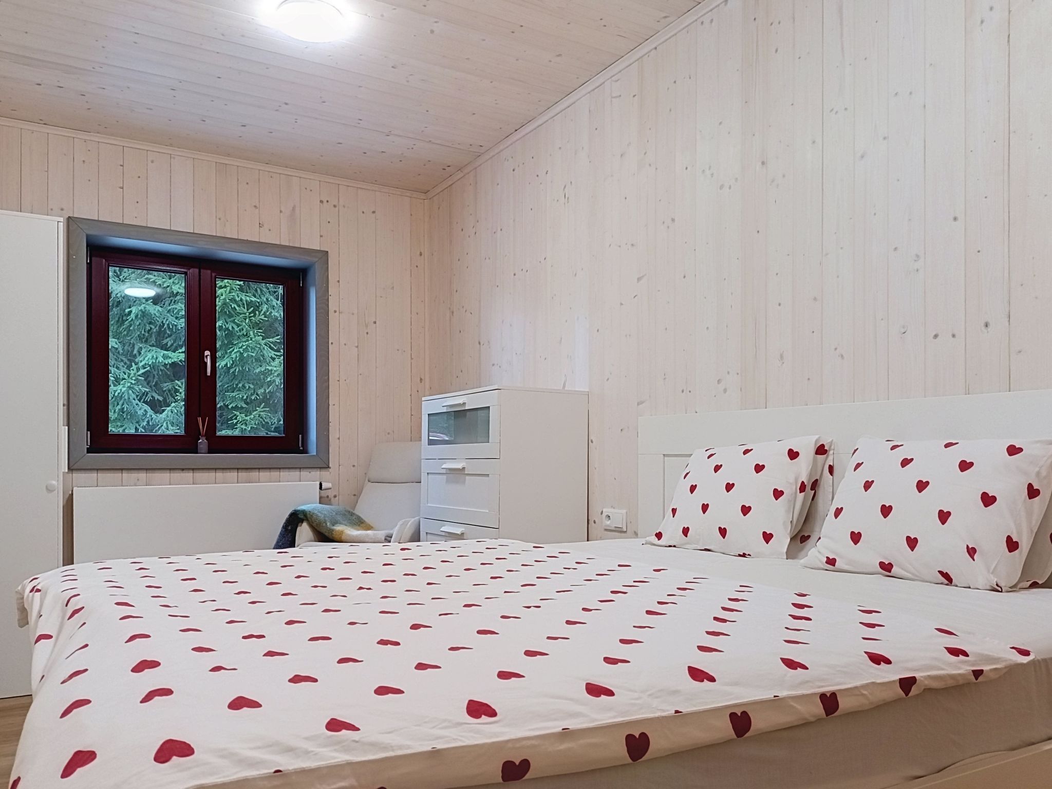 Une chambre à coucher avec un lit, une fenêtre, une commode et une table de chevet.