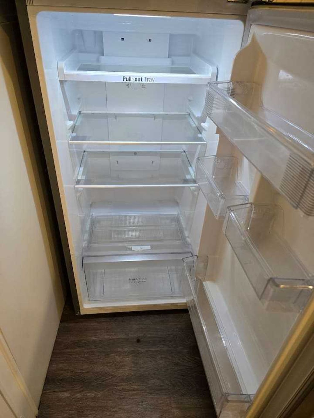 A refrigerator with a pull-out tray and multiple transparent shelves.