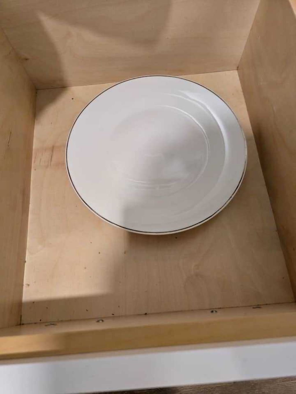 A white plate centered in a wooden box.