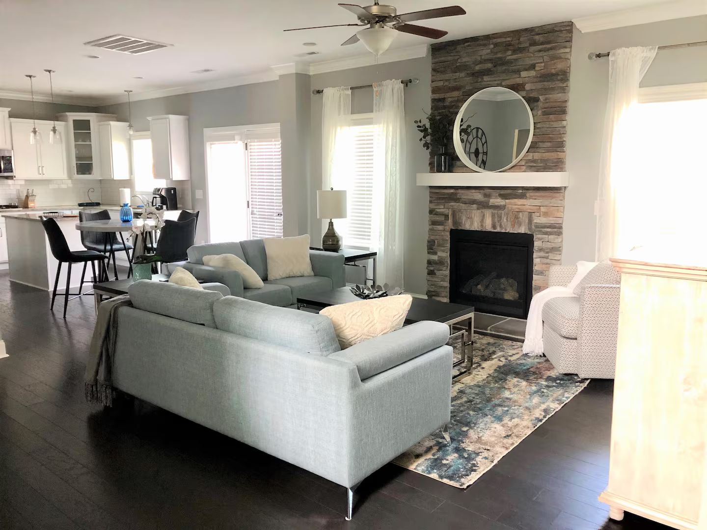 A modern living room with a fireplace, a dining area, and a kitchen in the background.