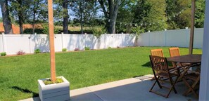 Ein Garten mit weißem Zaun, Rasen und einem Tisch mit Stühlen.