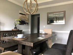 A dining area with a dark wooden table, two chairs, a chandelier, and wall art. - Great Family place to stay out of the city (High Point)