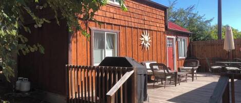 Une terrasse en bois avec des meubles d’extérieur, un barbecue et un espace clôturé.