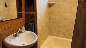 A bathroom with a white sink, a bathtub, and a shower curtain. - Little Strawberry Suites, Tiny Home Downtown Prairie City (Prairie City)