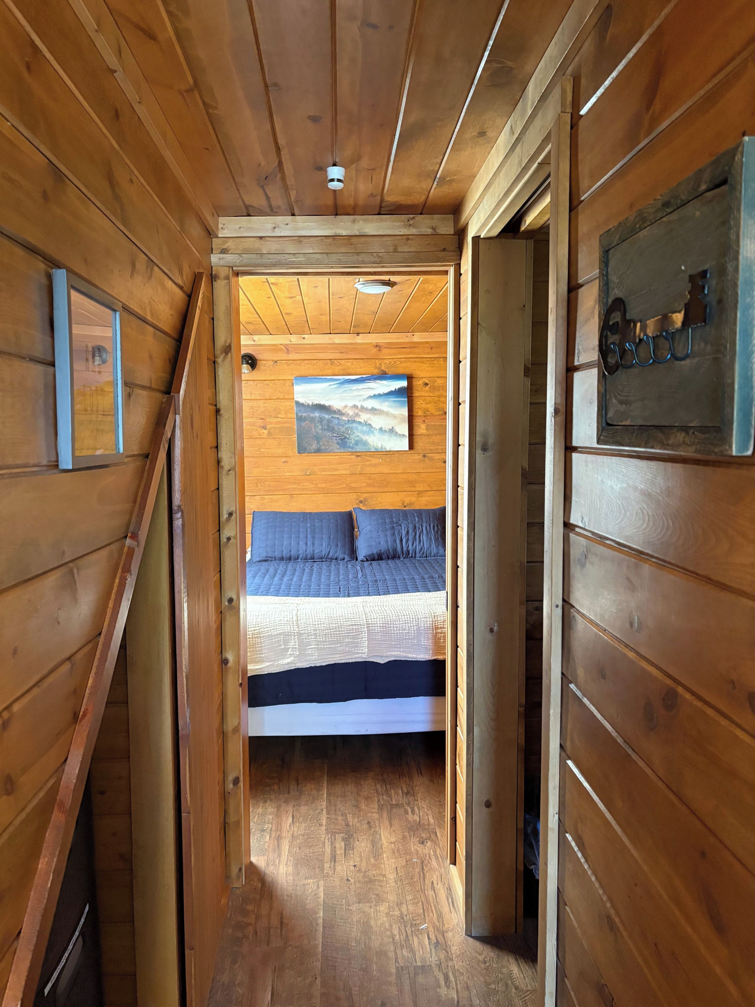 A wooden interior with a bed, a painting, and a metal sign.