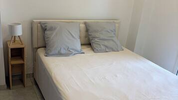 Una camera da letto con un letto, due cuscini, un comodino e una lampada.