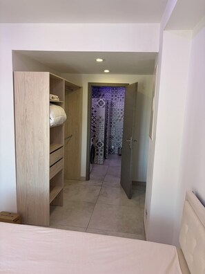 Un dormitorio con cama, armario de madera y baño con baldosas estampadas.