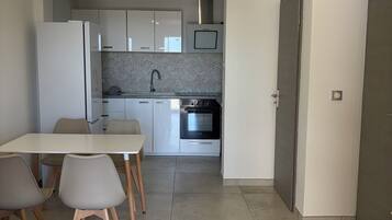 Una cucina moderna con mobili bianchi, forno a incasso e zona pranzo con tavolo e sedie.
