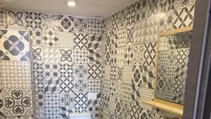 A bathroom with patterned tiles, a toilet, a sink, and a mirror. - Vrbo Property (Sausset-les-Pins)