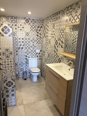 Een badkamer met patroon tegels, een toilet, een wastafel en een spiegel.