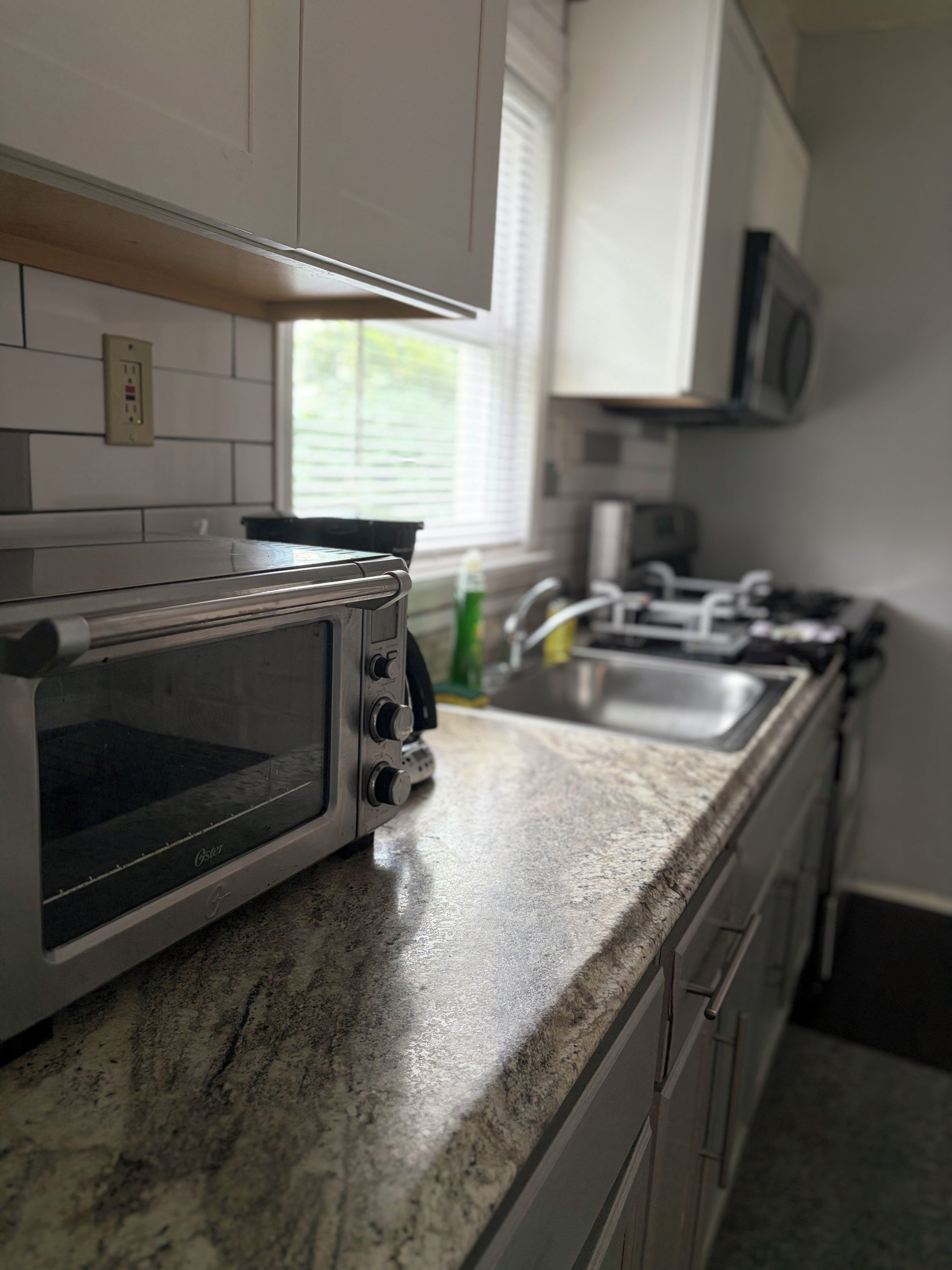 Una cocina con horno tostador integrado, microondas, lavaplatos y armarios.
