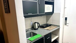Eine kleine Küche mit Mikrowelle, Wasserkocher und einer Arbeitsplatte.