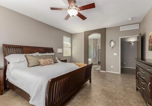A bedroom with a wooden bed, a ceiling fan, a dresser, and a walk-in closet. - Relaxing 3BR Avondale Home with Private Pool - Monthly Stays (Avondale)