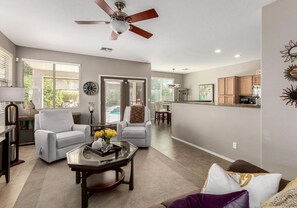 A spacious living area with a ceiling fan, a dining area, and a kitchen.