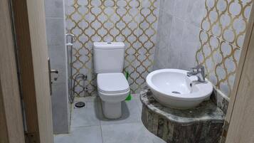 Une salle de bain comprenant des toilettes, un lavabo et un espace douche.