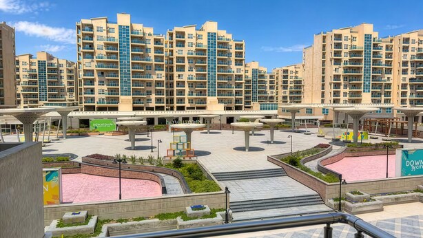 A residential complex with multiple high-rise buildings, a central courtyard with seating areas, and a pink water feature. - Apartment in New Alamein
Furnished Apartment for Rent in Downtown New Alamein (Marsa Matrouh Governorate)