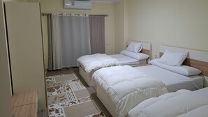A hotel room with two single beds, a wardrobe, a ceiling-mounted air conditioner, and a patterned rug. - Apartment in New Alamein
Furnished Apartment for Rent in Downtown New Alamein (Marsa Matrouh Governorate)