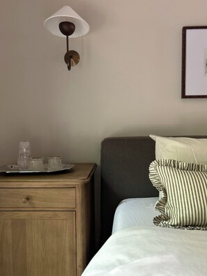 A neatly arranged hotel room with a bed, bedside table, lamp, and a framed picture on the wall.