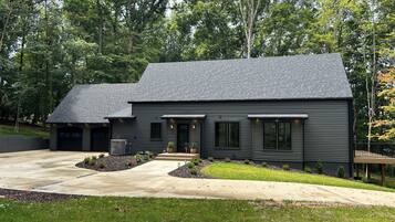 A modern two-story house with a dark exterior, a driveway, and a well-maintained lawn.