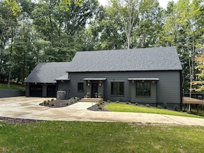 A modern two-story house with a dark exterior, a driveway, and a well-maintained lawn.