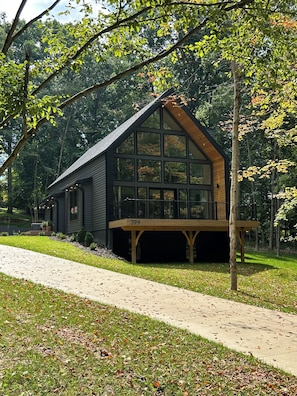 Une maison à deux étages avec une grande fenêtre au premier étage, une terrasse et le numéro 399 sur la façade.