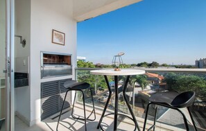 A balcony with a grill, two chairs, and a table. - Fully Equipped Apt, Pool & Workspace, City Views (Asunción)