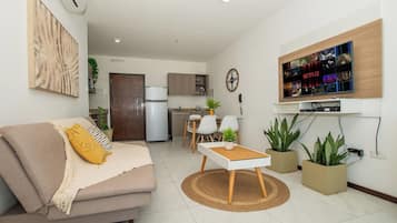 A modern living room with a sofa, coffee table, and a flat-screen TV mounted on the wall.