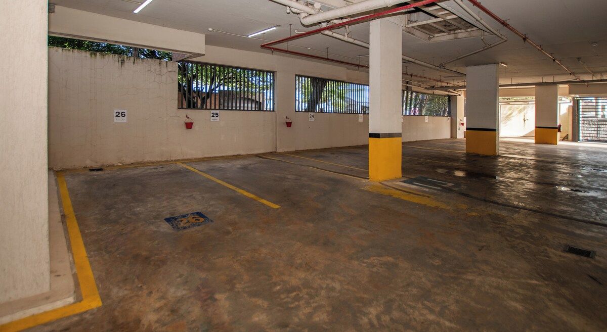A parking garage with numbered parking spaces, concrete floors, and pillars.