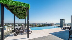A rooftop pool area with a pergola covered in greenery, lounge chairs, and a clear view of the cityscape. - Fully Equipped Apt, Pool & Workspace, City Views (Asunción)