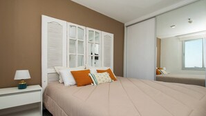 A bedroom with a large bed, a nightstand with a lamp, and a wardrobe with sliding doors. - Fully Equipped Apt, Pool & Workspace, City Views (Asunción)